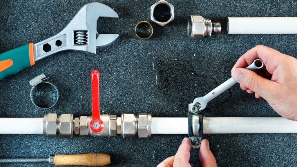 Plumber repairing a pipe valve with an adjustable wrench in Miami Beach