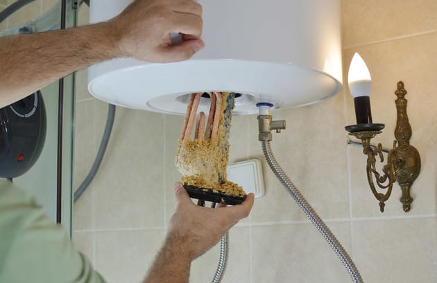Technician removing mineral buildup from a water heater in Miami Beach