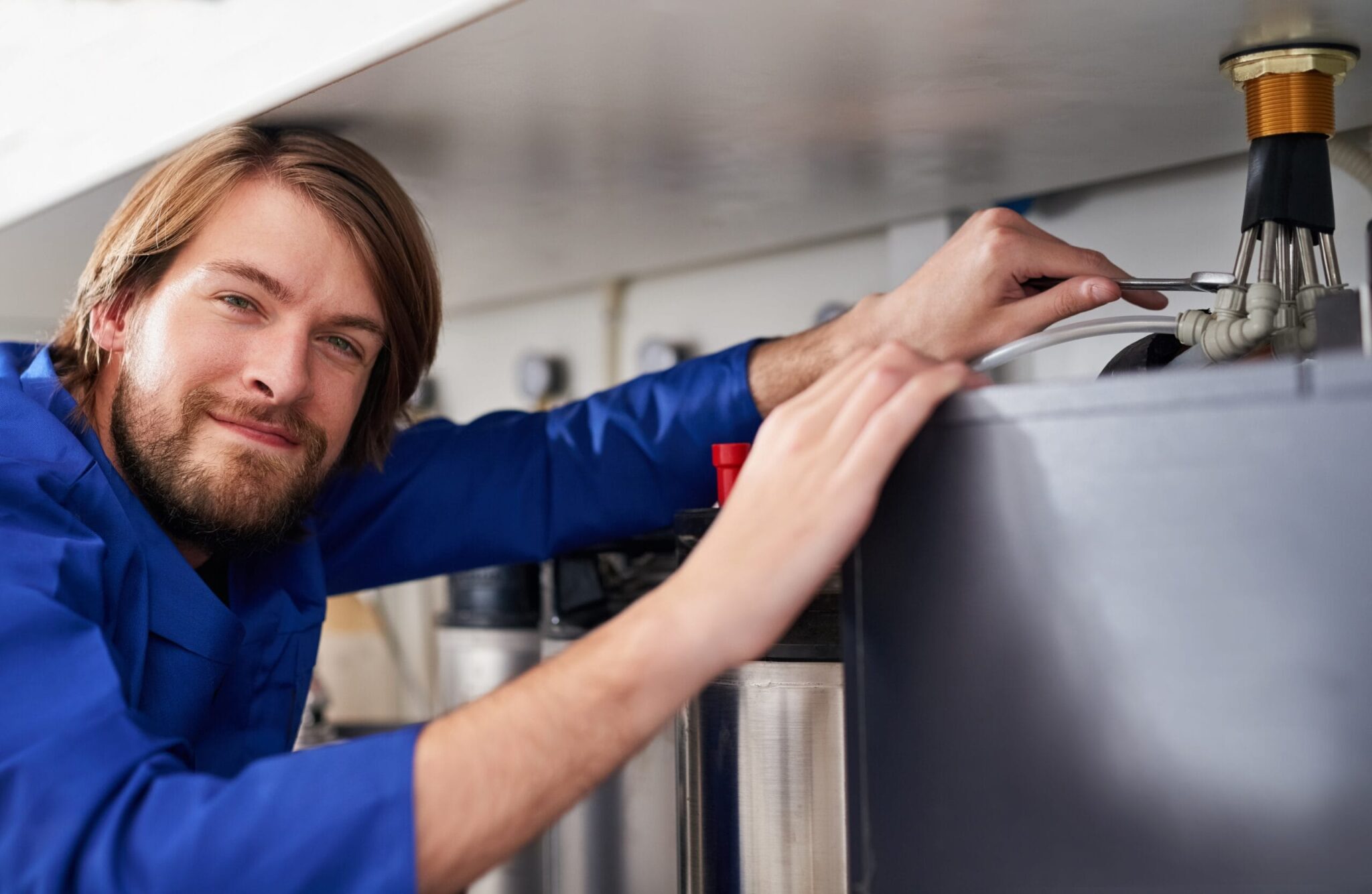 Technician servicing a residential water heater tank in Miami Beach
