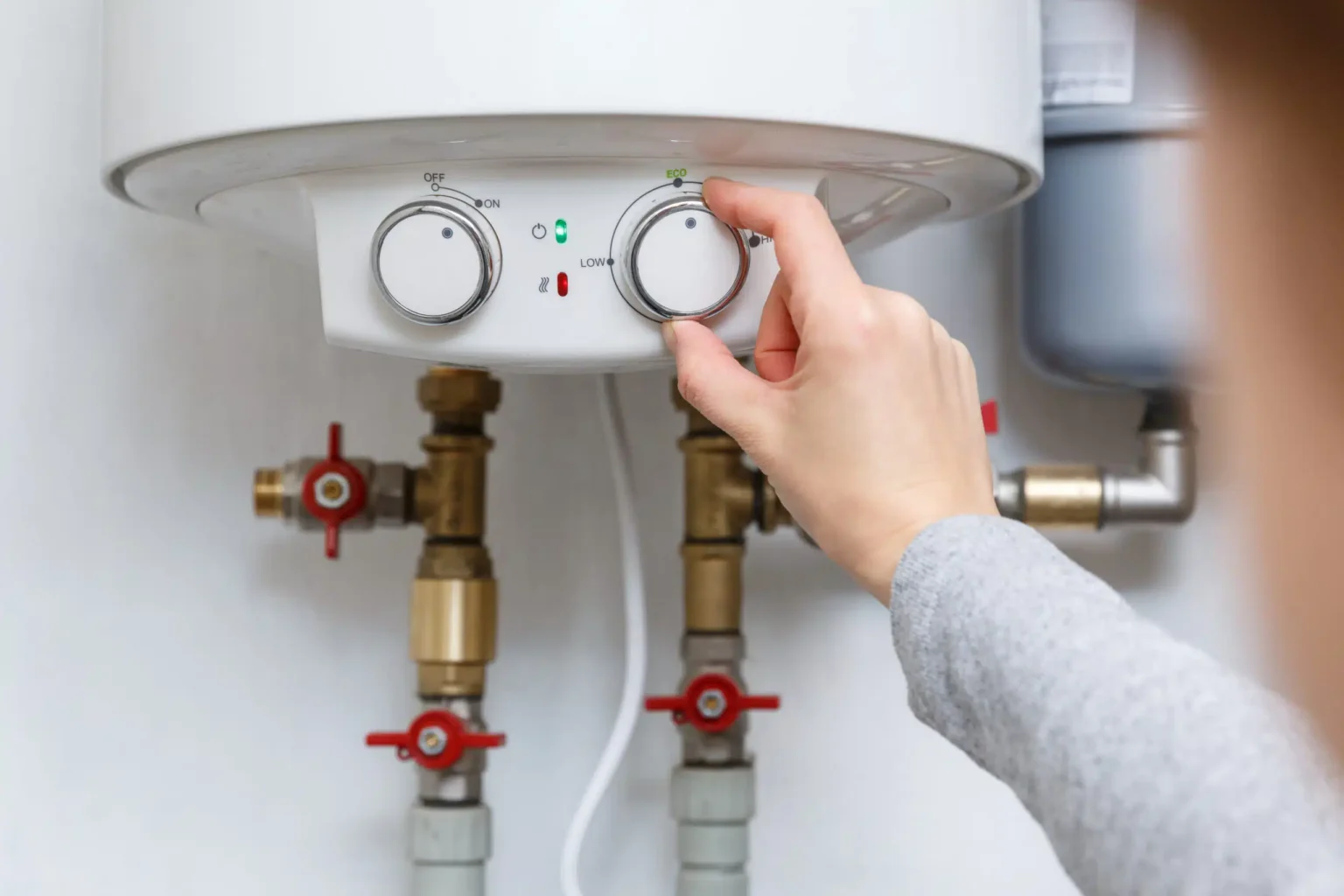Homeowner adjusting the temperature controls on a water heater in Miami Beach
